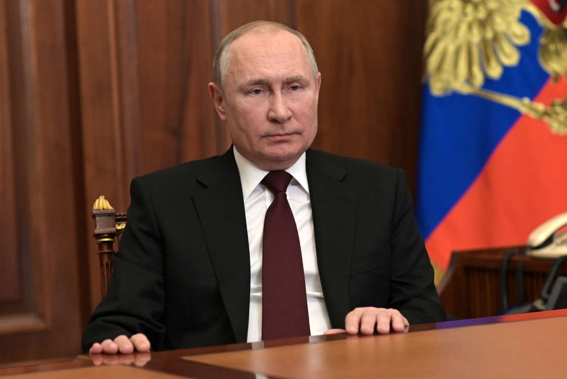 NÃO USAR ESSA FOTO - Presidente russo, Vladimir Putin, sentado com as mãos sobre uma mesa e com a bandeira da Rússia atrás