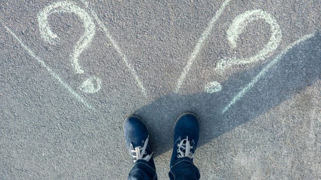 Pessoa em pé na frente de duas estradas dúvida carreira