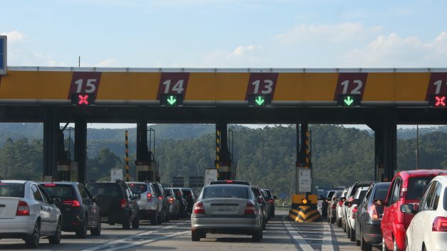 Carros enfileirados antes da praça de pedágio na Rodovia Anhanguera (SP-330) e ilustrando as ações de concessionárias na bolsa