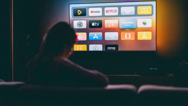 Televisão smart mostrando uma pessoa assistindo