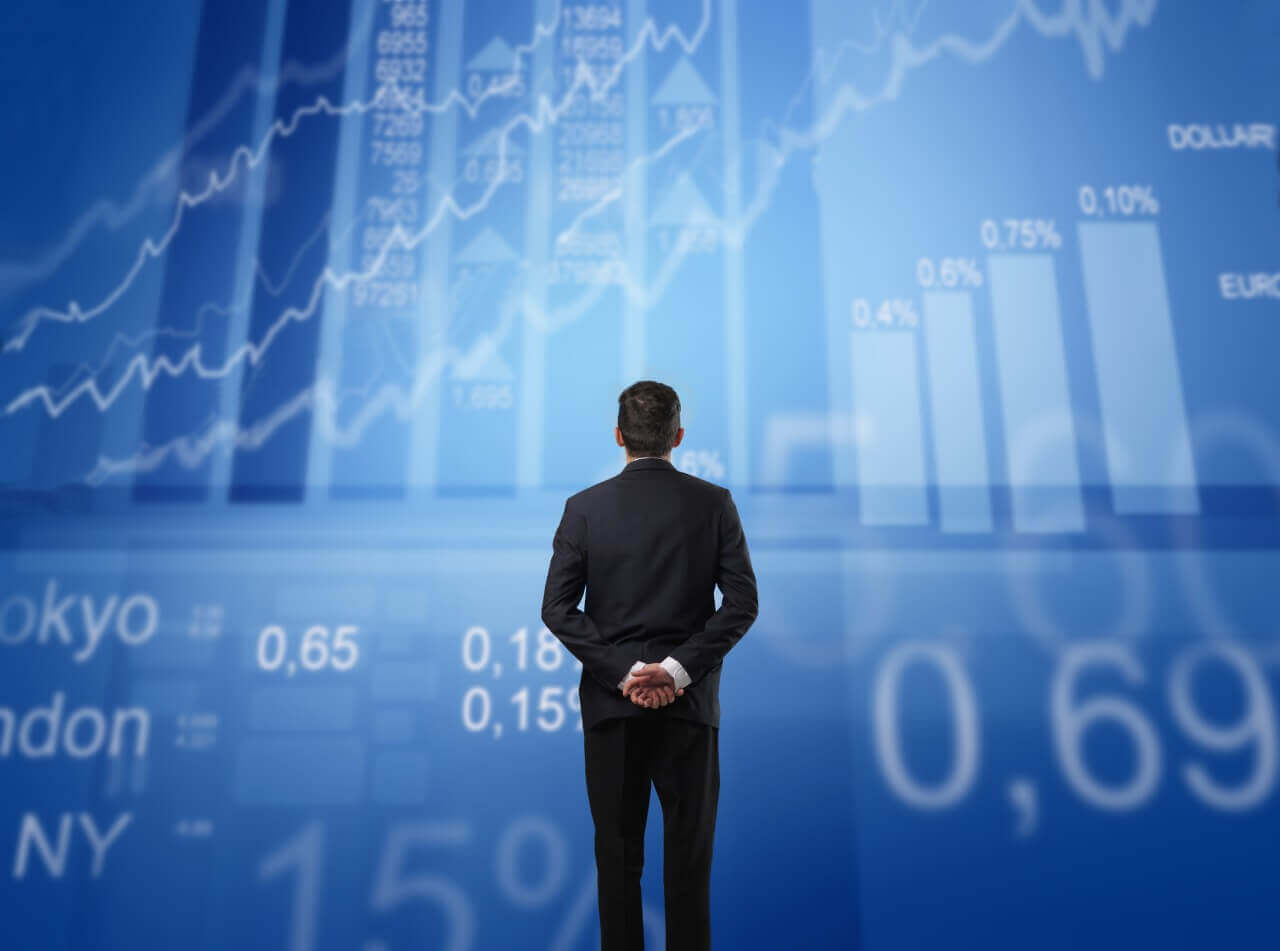 Investidor olha para tela de cotações e gráficos da bolsa