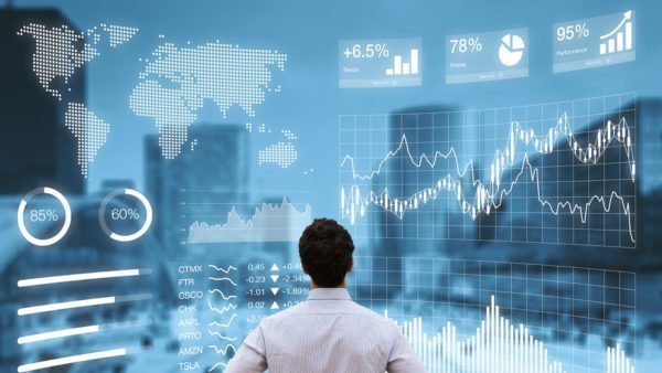 Investidor olha para tela de cotações e gráficos da bolsa.