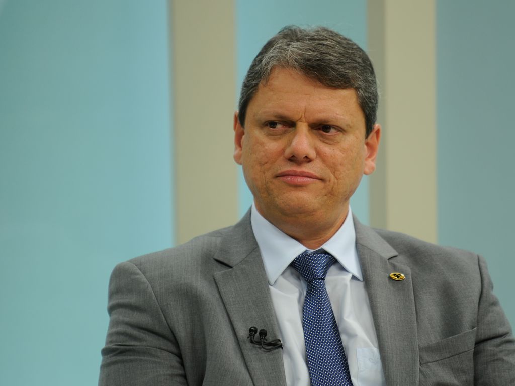 Foto de meio corpo de homem vestido terno cinza, camisa branca e gravata azul