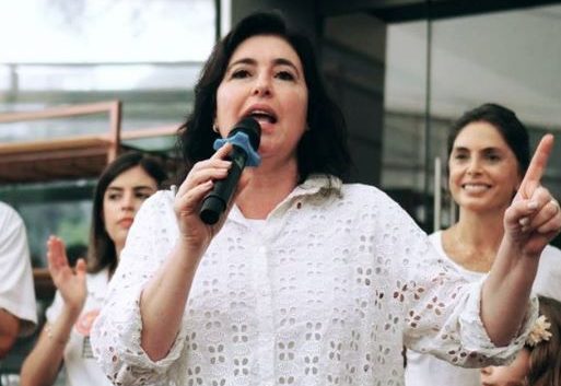 Story da senadora Simone Tebet (MDB), que veste camisa branca furadinha e está com microfone na mão