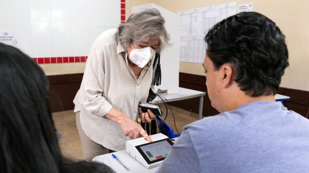 Idosa se identifica com biometria antes de votar no primeiro turno de 2022, em 2 de outubro.