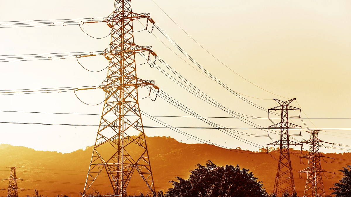 electricity transmission pylon silhouetted against blue sky at d