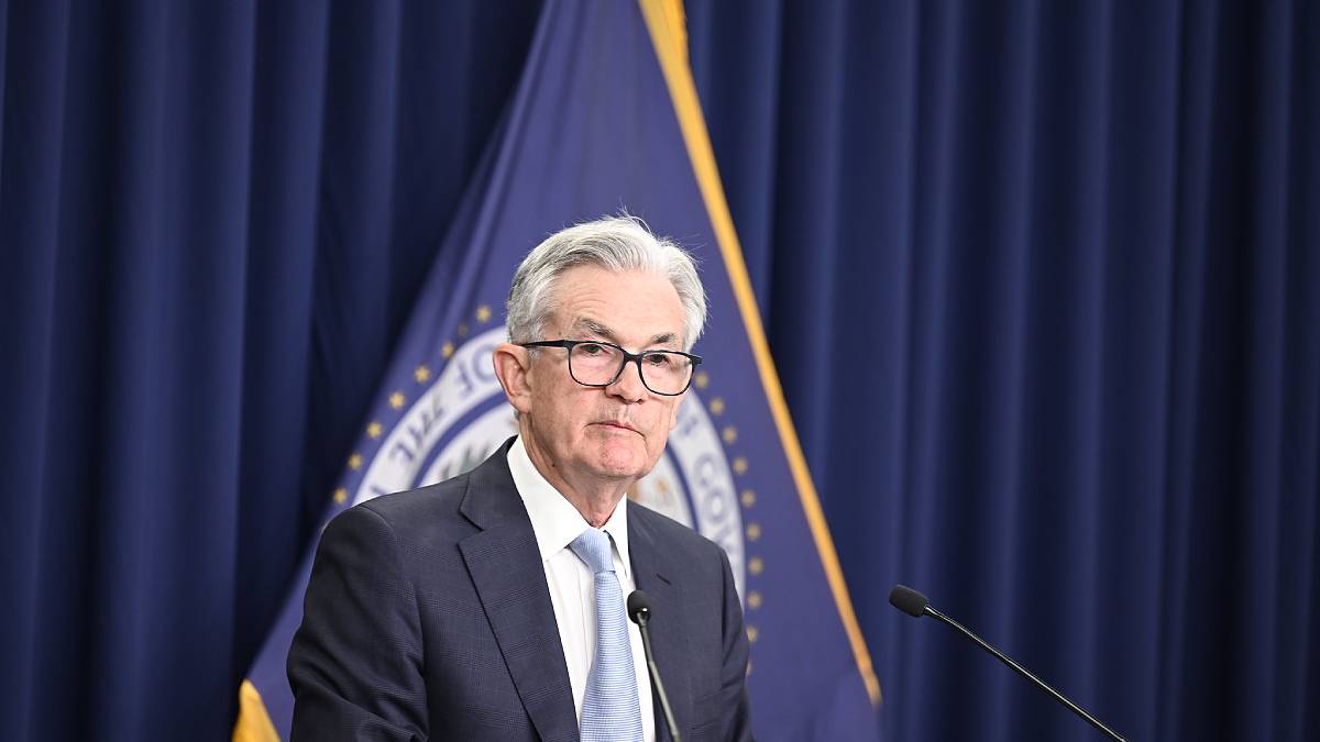 O presidente do Federal Reserve (Fed), Jerome Powell, de pé, em frente a um púlpito com microfone e bandeira do BC dos EUA ao fundo