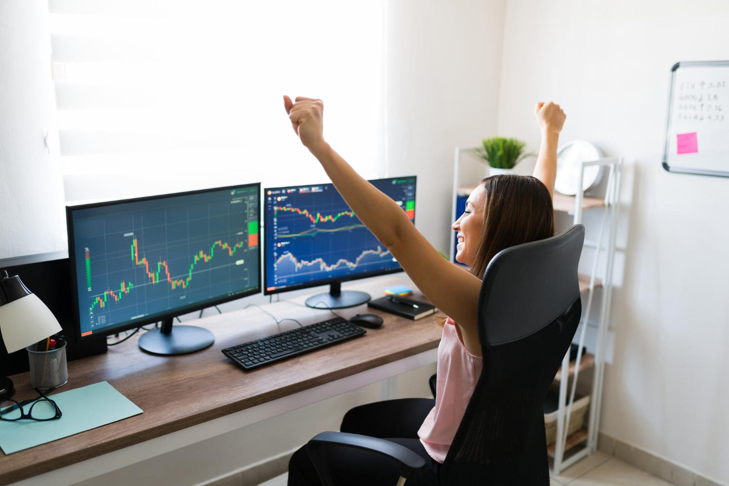 Investidora mulher comemorando enquanto olha para tela de computador com gráficos