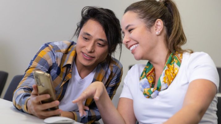 Duas pessoas observando informações em um celular; dia do estagiário; estágio