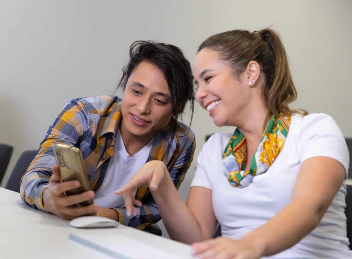 Duas pessoas observando informações em um celular; dia do estagiário; estágio
