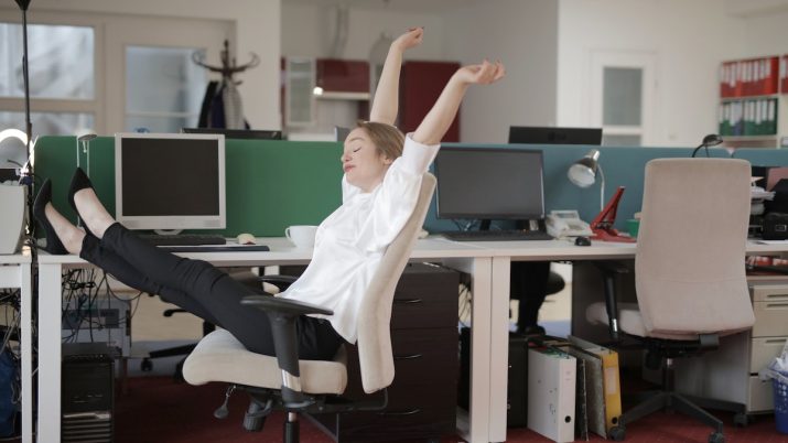 Moça se espreguiça no ambiente de trabalho