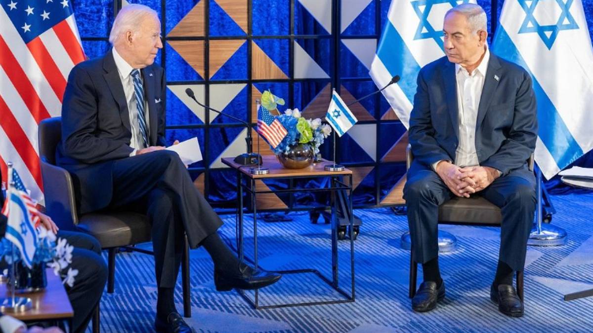 O presidente dos EUA, Joe Biden, está sentado perto do primeiro-ministro de Israel, Benjamin Netanyahu. Entre eles uma mesa de centro e atrás deles bandeiras dos EUA e de Israel.