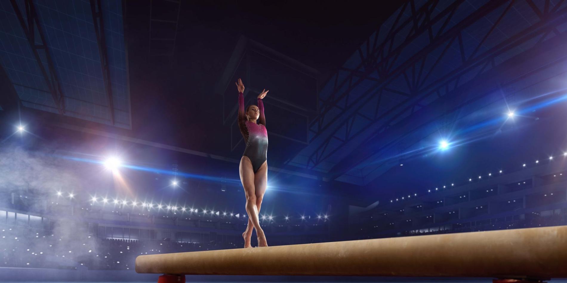 jpeg-optimizer_ginasta-feminina-fazendo-um-truque-complicado-na-trave-de-equilibrio-de-ginastica-em-uma-arena-profissional