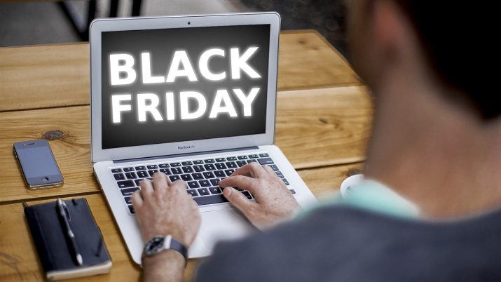 Homem escrevendo no computador portátil e a tela em preto com Black Friday em branco, ao centro