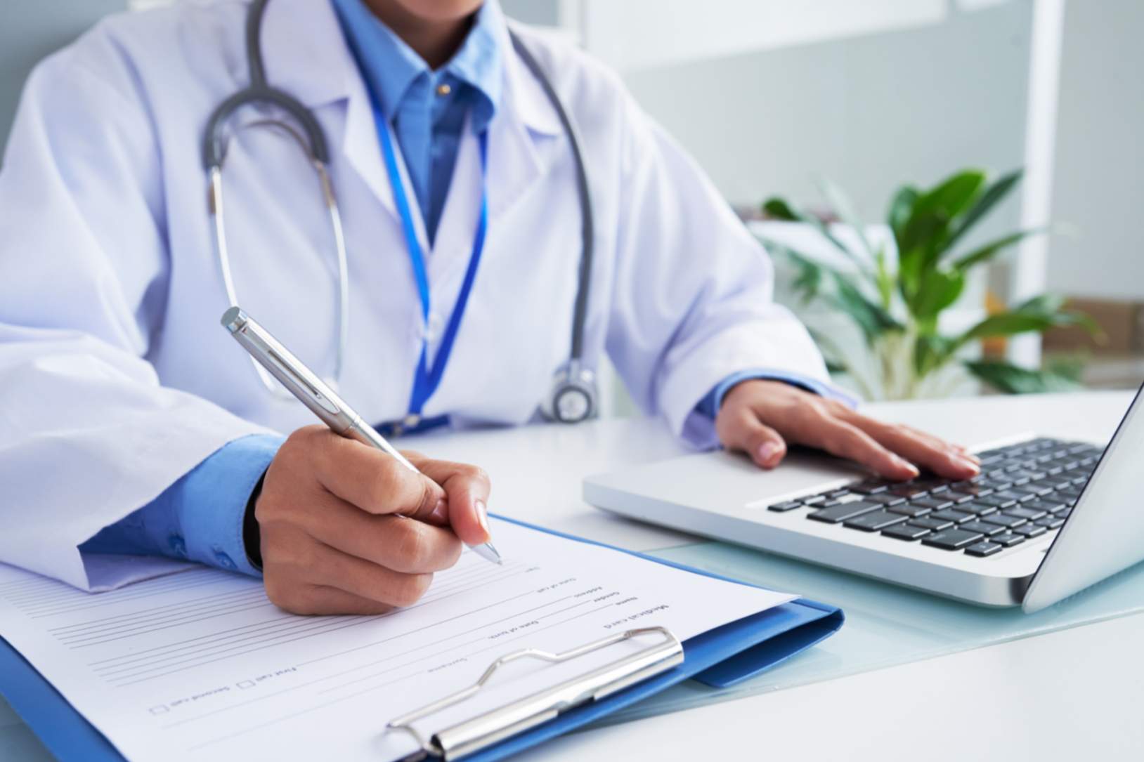 jpeg-optimizer_maos-da-medica-irreconhecivel-escrevendo-no-formulario-e-digitando-no-teclado-do-laptop
