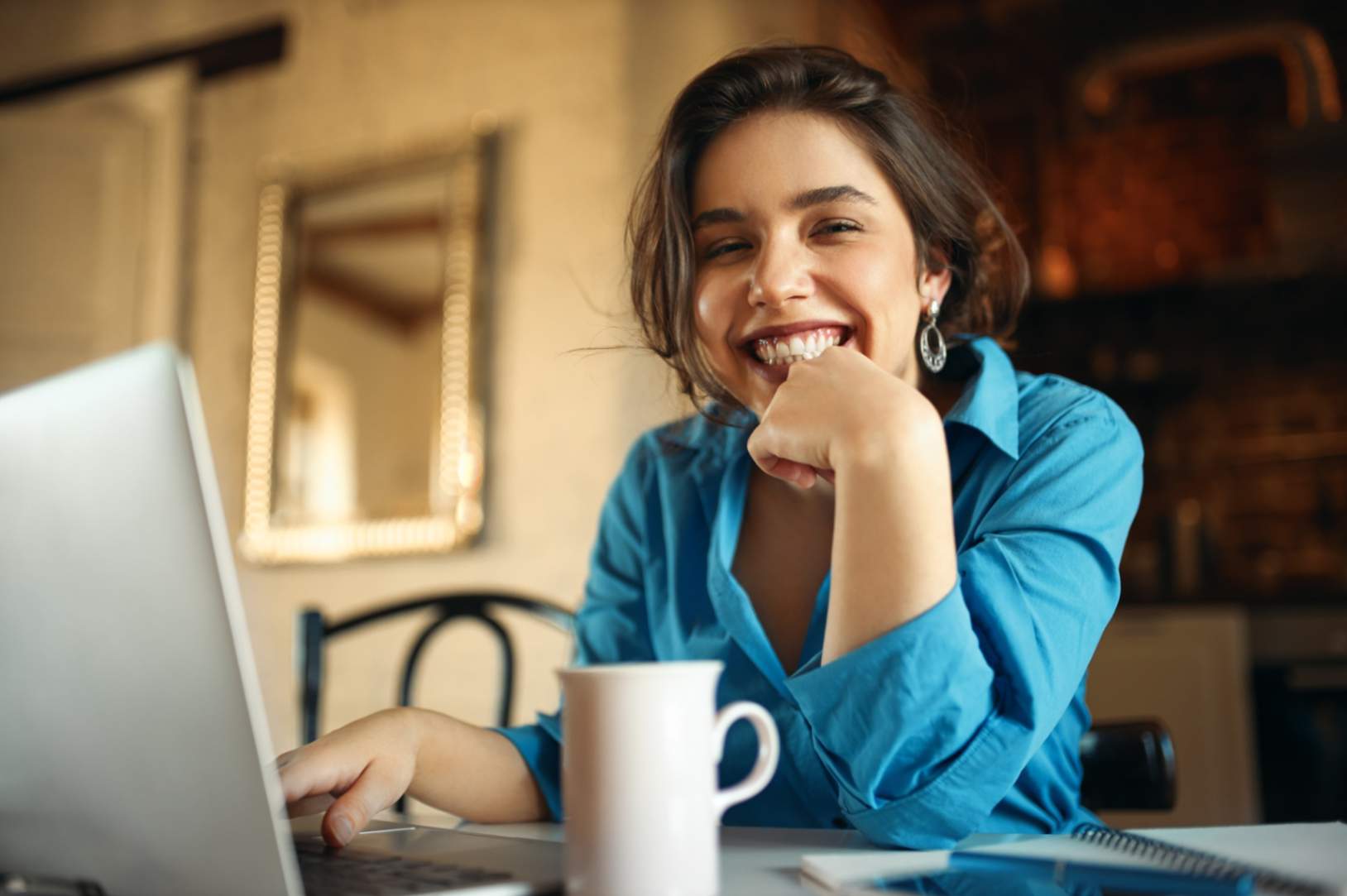 jpeg-optimizer_mulher-jovem-e-atraente-alegre-apreciando-um-trabalho-distante-sentado-na-mesa-usando-um-computador-portatil-bebendo-cafe-blogueira-bonita-trabalhando-em-casa-enviando-video-em-seu-canal-