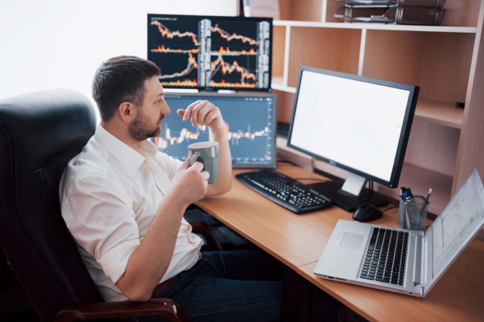 jpeg-optimizer_jovem-empresario-esta-sentado-no-escritorio-a-mesa-trabalhando-no-computador-com-muitos-monitores-diagramas-no-monitor-corretor-da-bolsa-analisa-graficos-de-opcoes-binarias-homem-moderno-