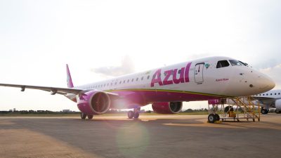 Avião branco e rosa da companhia de aviação Azul. A aeronave está estacionada.
