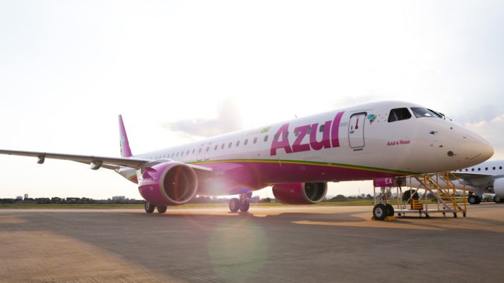 Avião branco e rosa da companhia de aviação Azul. A aeronave está estacionada.