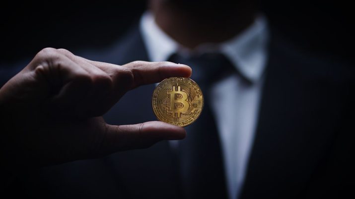 Homem segurando criptomoeda (bitcoin)