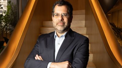 Marcelo Nantes de Souza, head de renda variável do Asa, diante de uma escada marrom. Ele está de terno e usa óculos, moreno.