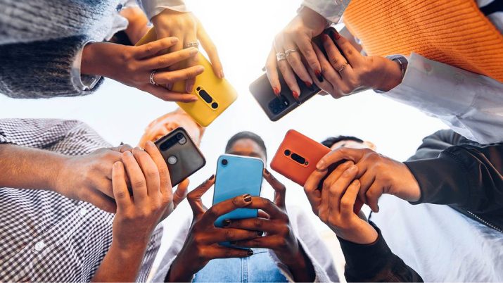 Jovens formam um círculo e seguram celulares coloridos