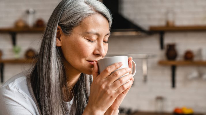 Asiático tomando café um xícara branca.