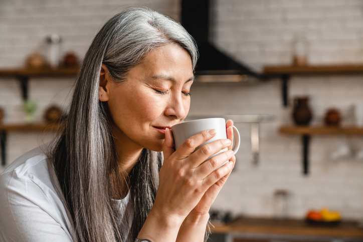 Asiático tomando café um xícara branca.
