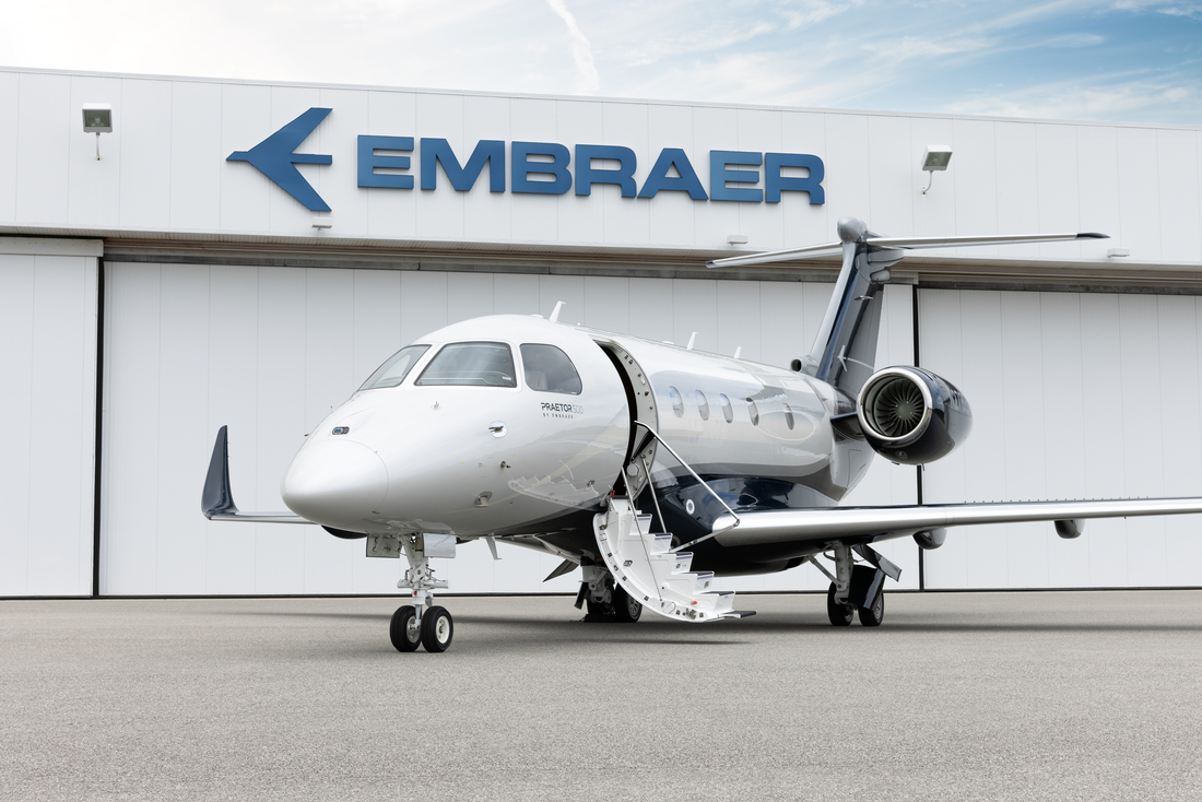 Um jato executivo da Embraer, o PRAETOR 500, em frente a marca da companhia.