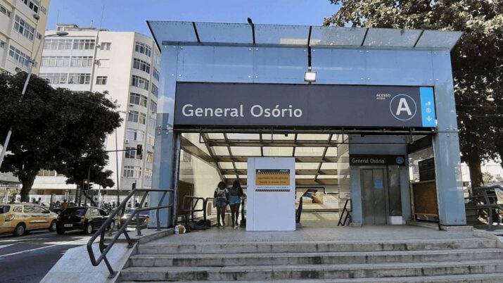 Entrada da estação General Osório do metrô do Rio de Janeiro, com pedestres e táxis ao fundo, em dia ensolarado.