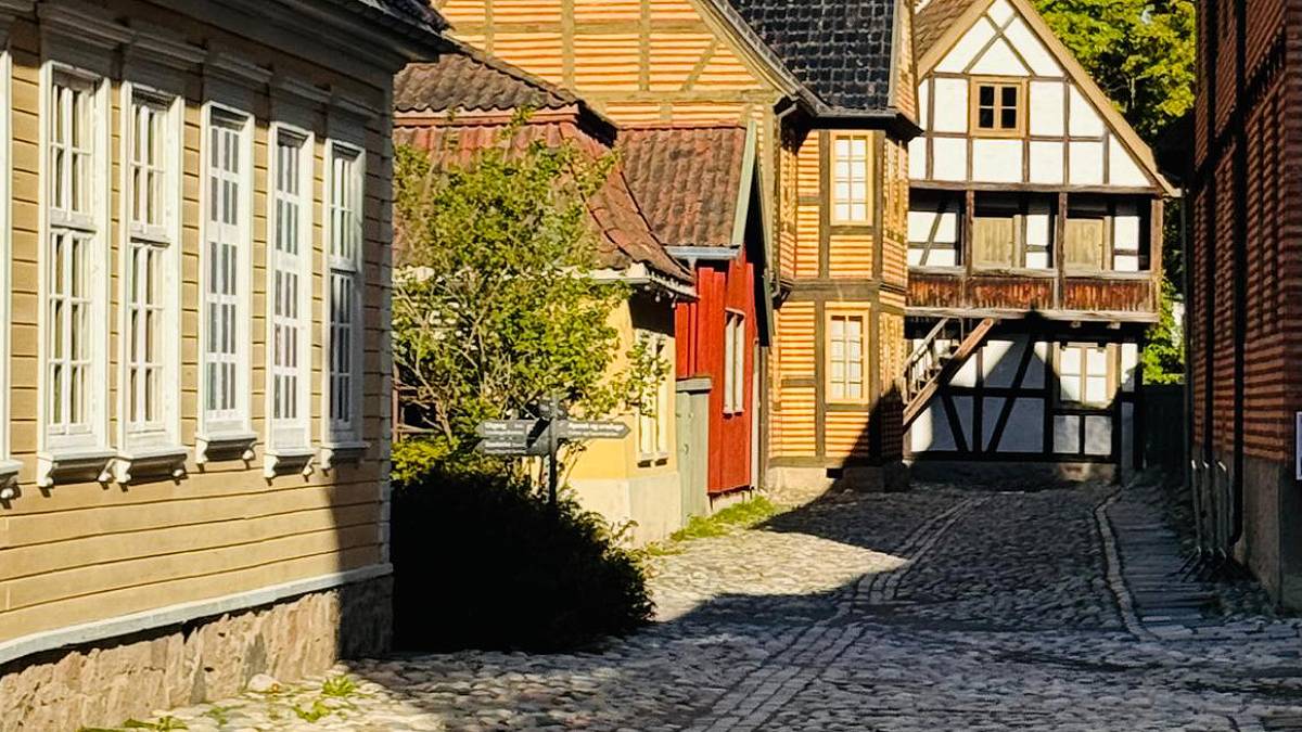Foto de uma rua de pedras com casas típicas da Noruega: coloridas e de madeira