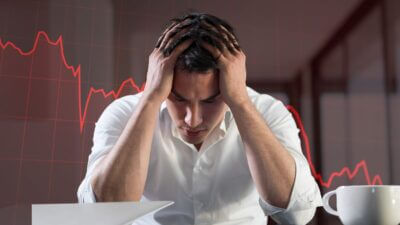 Investidor diante de um gráfico vermelho de queda