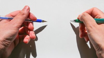 Mãos de pessoa ambidestra escrevendo com as duas mãos ao mesmo tempo