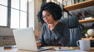 Gerente empresária investidora jovem feliz olhando para a tela do computador lendo e-mail trabalhando em projeto no escritório