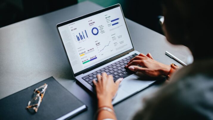 Computador com gráficos do mercado financeiro e as mãos de uma mulher