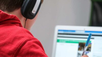 Jovem olhando para a tela de um notebook e usando fones de ouvido