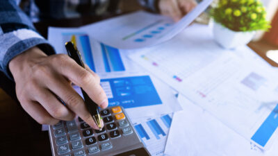 Close up businessman using calculator and reading paper document about business data, accountancy document, graph profit company.