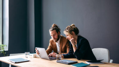 Two Smiling Colleagues Working Together On A New Project