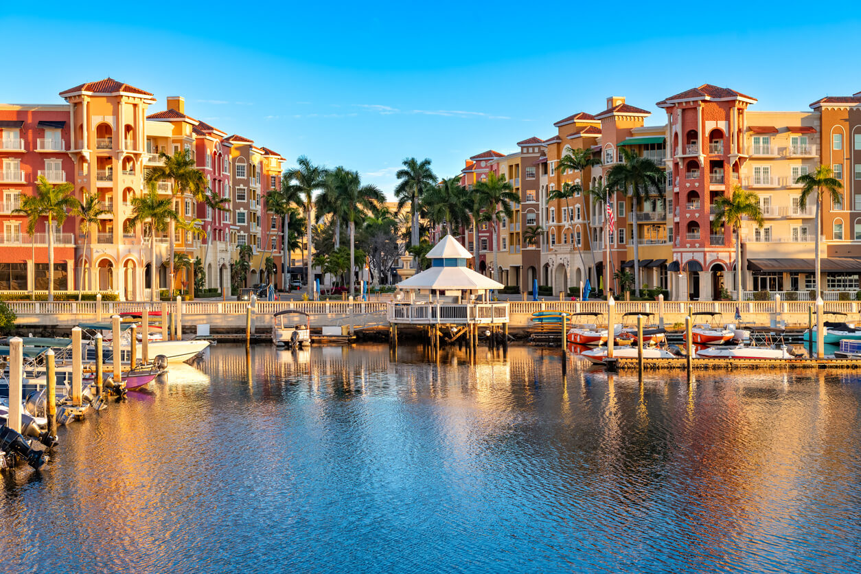 Morning light on Naples with waterfront buildings and boats under a clear sky. 