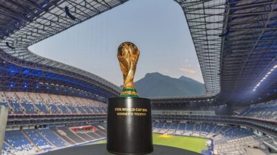 Troféu da Copa do Mundo 2026 com estádio atrás - Imagem: Reprodução/Metlife Stadium