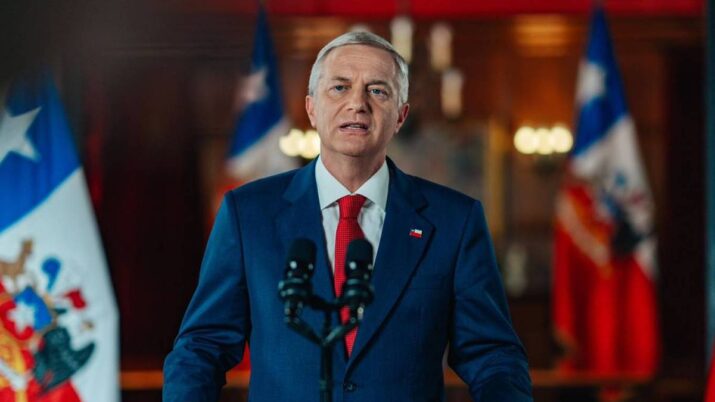 Imagem do presidente do Chile, José Antonio Kast. Ele está de pé, de terno azul marinho, em frente à bandeira do país