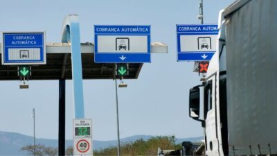 Placas de pedágio na rodovia, escritas em português, Brasil.