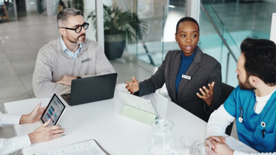 Doctors, nurses and discussion with tablet in clinic for medical results, health stats or feedback. Above, people or medicine team with screen for hospital budget, surgery planning or healthcare cost