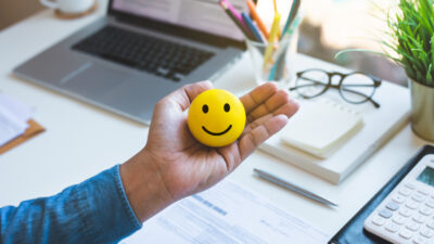Emoticon ball on male hand on work table.happy life concepts.