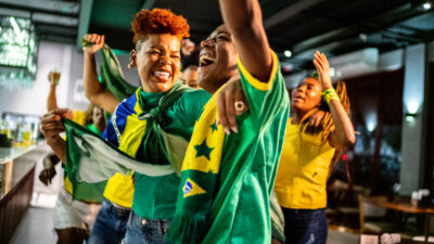 Brazilian sports fans watching match and celebrating at a bar