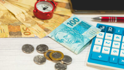 Brazilian Real banknotes and coins on a wooden table. A calculator in the composition. Brazilian economy and finance.