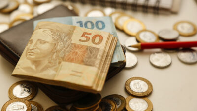 fifty reais notes and other notes and coins on the table with wallet, pencil and notebook