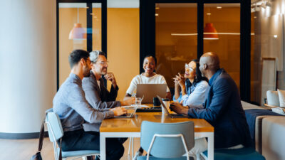 Group discussing strategies in an office with laptops and cheerful interaction