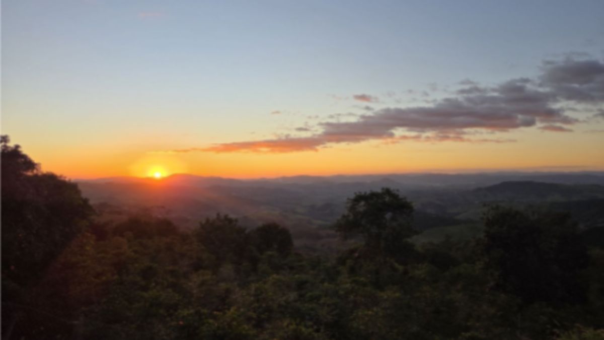 Foto de um horizonte nas montanhas, com árvores e o sol se pondo.