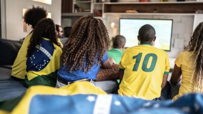 Pessoas torcendo para o Brasil na Copa do Mundo no sofá de casa